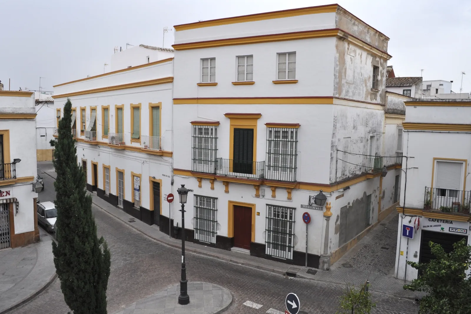 A bend in a San Miguel street in Jerez, with white town houses trimmed in yellow ochre and a tall cypress tree